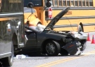 A car sits mangled between a school bus and a UPS truck following the crash in the Hamilton area, Monday, June 21, 2010.