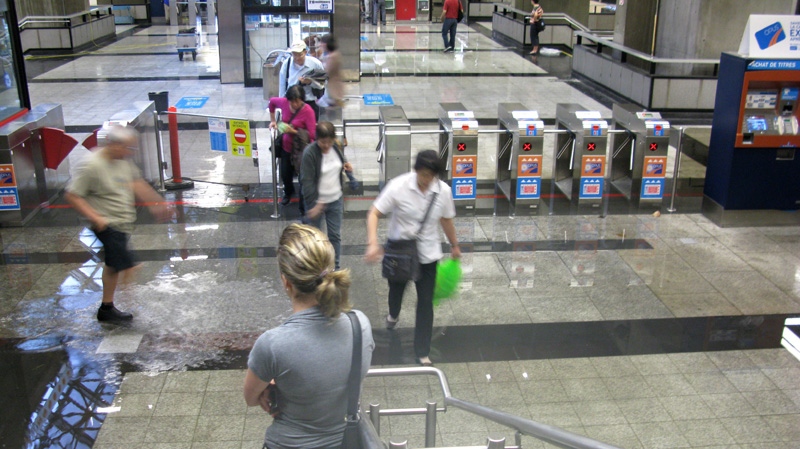 A woman wait at the bottom of the steps as other people walk though water at the Place d'Armes metro station in Montreal on Tuesday, May 29, 2012. (Andy Blatchford / THE CANADIAN PRESS)