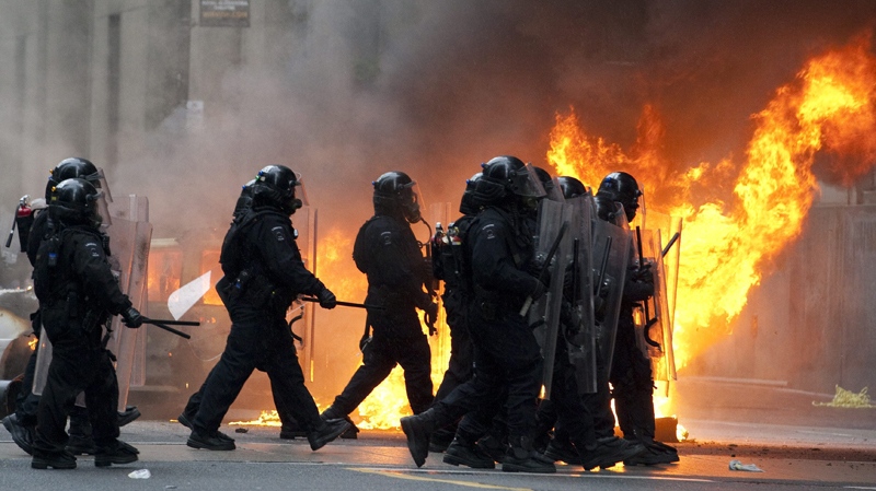 Riot police walk by a burning police cruiser in downtown Toronto during anti G20 protests on Saturday, June 26, 2010. (Frank Gunn / THE CANADIAN PRESS)        
