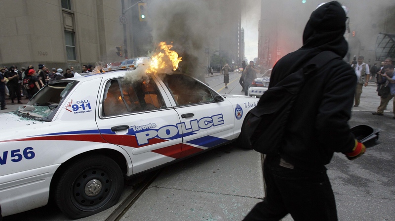 Protesters surround a burning police car at King and Bay streets during demonstrations in downtown Toronto Saturday, June 26, 2010. (AP / Gerry Broome)