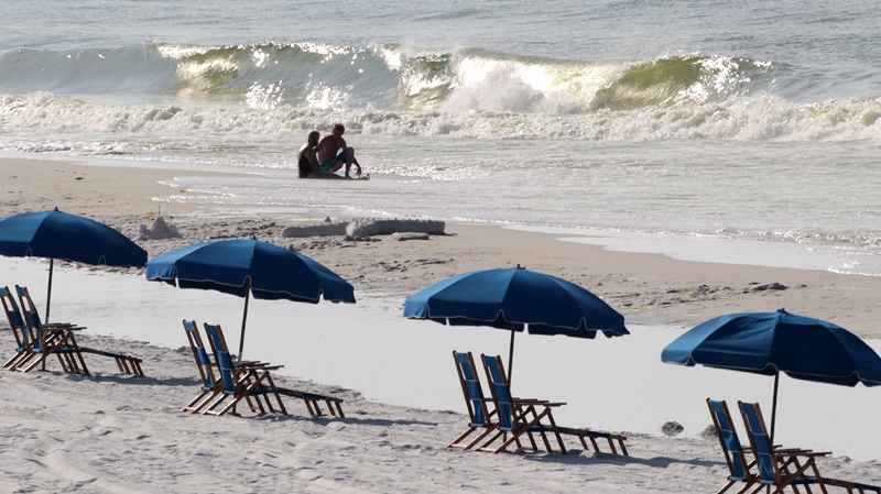Sun bathers sit in the surf near empty beach chairs in Destin, Fla., Sunday, June 27, 2010. Tourist businesses from Pensacola to Panama City are feeling the full financial crunch of the massive oil spill, as normally packed parking lots sat nearly empty. (AP / Dave Martin)