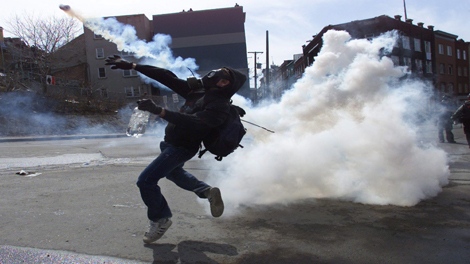 FILE--A demonstrator throws a tear gas canister outside the site of the Summit of the Americas in Quebec City Saturday, April 21, 2001. (THE CANADIAN PRESS/Kevin Frayer)