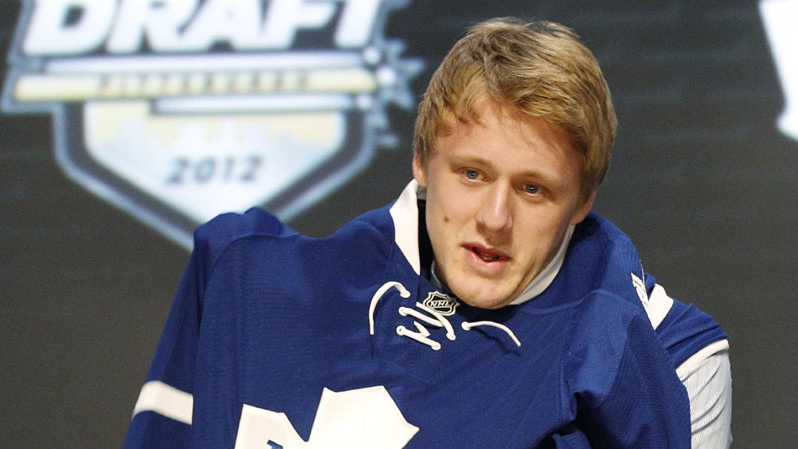 Morgan Rielly pulls on a Toronto Maple Leafs sweater 