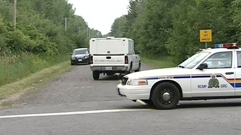 Police block off access to a road where a body was found in a car that went up in flames near the Mer Bleue Bog, Tuesday, July 6, 2010.