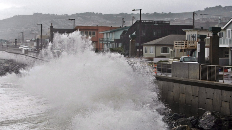 Waves pound a wall near buildings in Pacifica, Calif. 