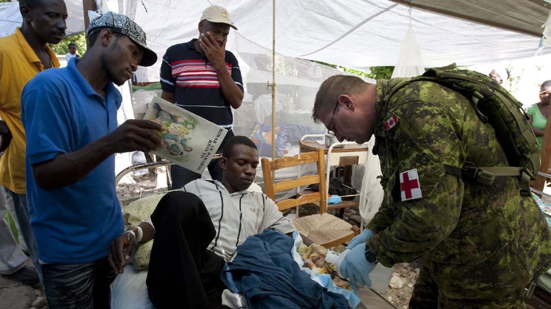 Petty Officer Paul Spracklin is watched as he tends to a man with a foot injury at the hospital in Jacmel, Haiti Monday Janaury 18, 2010. (THE CANADIAN PRESS/Adrian Wyld)