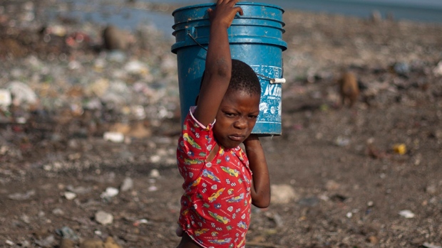 A boy carries home a bucket of water for bathing