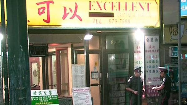 Police officers stand outside the Excellent Cantonese Seafood restaurant where a man was shot in Toronto's Chinatown area, Saturday, July 10, 2010.