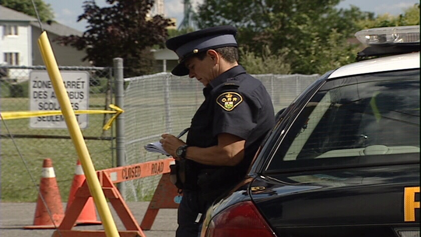 An Ontario Provincial Police officer stands outside a school in St. Isidore, Ont., east of Ottawa. 