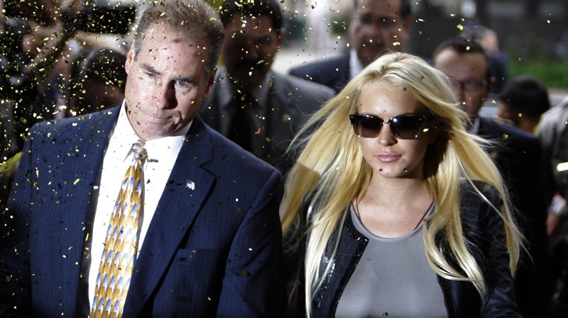Confetti flies as Lindsay Lohan, with an unidentified man, arrives at the Beverly Hills courthouse Tuesday, July 20, 2010. (AP / Reed Saxon)