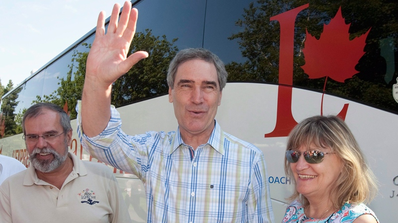 Liberal Leader Michael Ignatieff, flanked by his wife Zsuzsanna Zsohar and Liberal candidate Claude Morin, salutes the crowd as he arrives in Frampton, Que. on Wednesday, July 21, 2010 as part of his Canada wide tour. (Jacques Boissinot / THE CANADIAN PRESS)