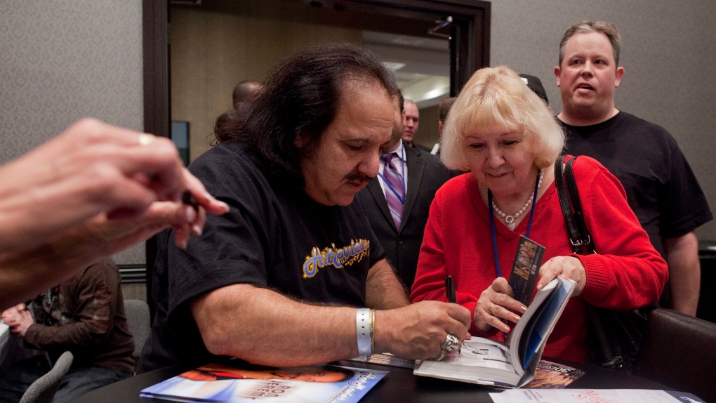 Adult film star Ron Jeremy, left, signs his book during the Adult Video Network Expo