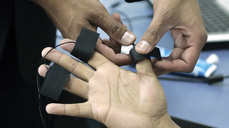 A polygraph examiner applies electrodes on the fingers of a student at the Latin American Polygraph Institute in Bogota, Colombia, on June 12, 2007. (AP Photo/Fernando Vergara)