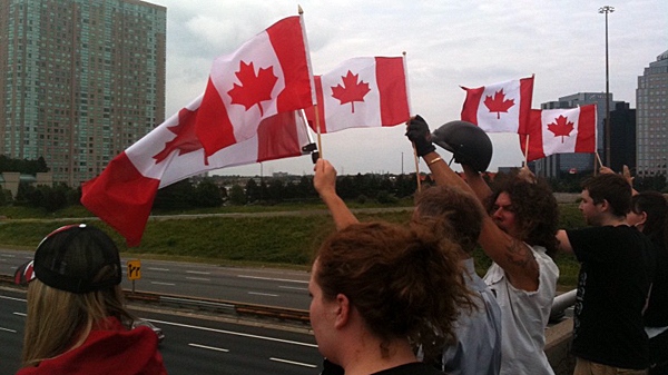 People wave flags on the McCowan Road overpass on Friday, July 23, 2010 as the motorcade transporting the body of Sapper Brian Collier approaches on the Highway of Heroes. (Bill Doskoch/ctvtoronto.ca)