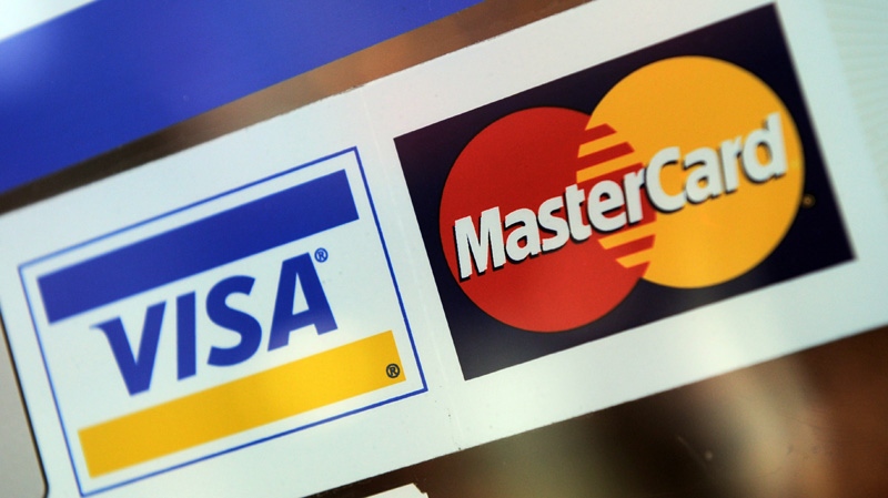 In ths May 8, 2012 photo, Visa and MasterCard signs are displayed on a store window in Ottawa.