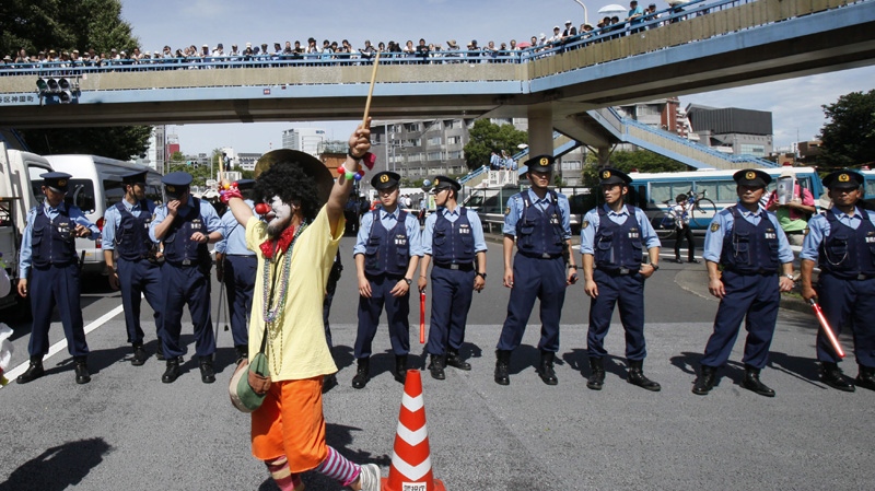 An anti-nuclear protester is watched by police officers in downtown Tokyo on  July 16, 2012.