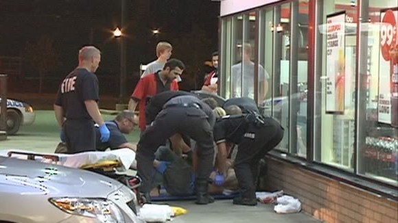 Paramedics treat a man Tuesday night outside a downtown Saskatoon convenience store.