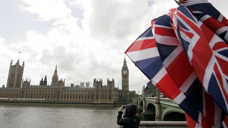 Union flags are seen at a souvenir shop as a tourist takes photographs of the Houses of Parliament in London, England, Monday, May 18, 2009. (AP / Akira Suemori)