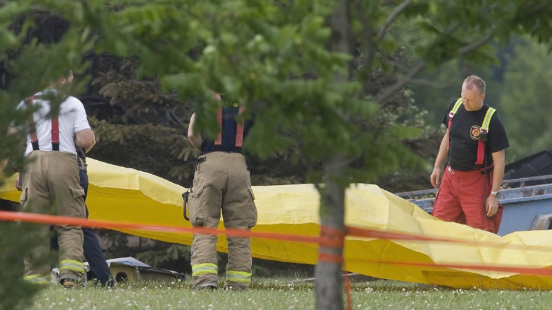 Firemen set up a yellow tarp near the crash site of an Aeropro Beechcraft King Air 100 in Quebec City, Wednesday June 23, 2010. The Beechcraft crashed shortly after take off near the airport. (Francis Vachon / THE CANADIAN PRESS)
