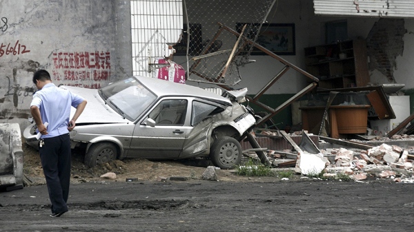 n this photo taken Sunday, Aug. 1, 2010, a policeman walks near a smashed car and shop at Yuanshi county, in north China's Hebei province. (AP Photo)