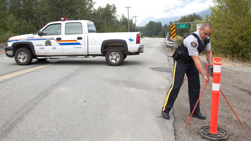 A member of the RCMP removes a barricade from a road just outside of Pemberton, B.C. on Saturday, August 7, 2010. (Jonathan Hayward / THE CANADIAN PRESS)