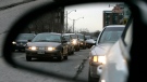 Commuters are reflected in a rearview mirror in rush hour traffic in Toronto. (J.P. Moczulski / THE CANADIAN PRESS)