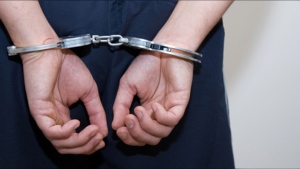 A file photo shows a person with their hands restrained in cuffs behind their back. 