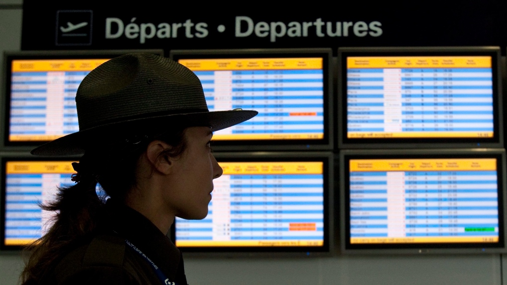 An airport security guard walks past a departures panel at the Montreal Trudeau airport, Tuesday, Ja