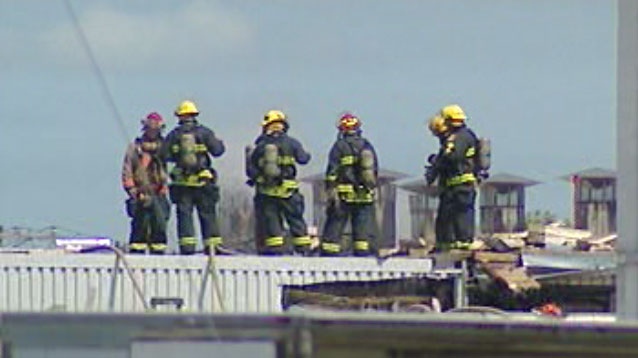 Fire crews stand on the roof of the Maple Leaf Foods plant in St. Boniface to battle a fire.