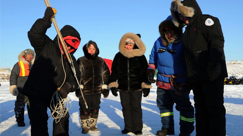 Prime Minister Stephen Harper, right to left, Canadian Ranger Dinos Tikivik, Leona Aglukkaq, Minister of Health and Minister of the Canadian Northern Economic Development Agency, Eva Aariak, Premier of Nunavut, look on as Moses Atagooyuk gives a seal hunting demonstration in Frobisher Bay in Iqaluit, Nunavut on Thursday, February 23, 2012. (Sean Kilpatrick / THE CANADIAN PRESS)