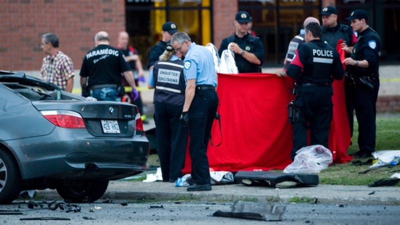 Police officers cover up bodies at a scene where two people were killed in a collision between a bus and two cars in Montreal, Tuesday, August 14, 2012. (Graham Hughes / THE CANADIAN PRESS)