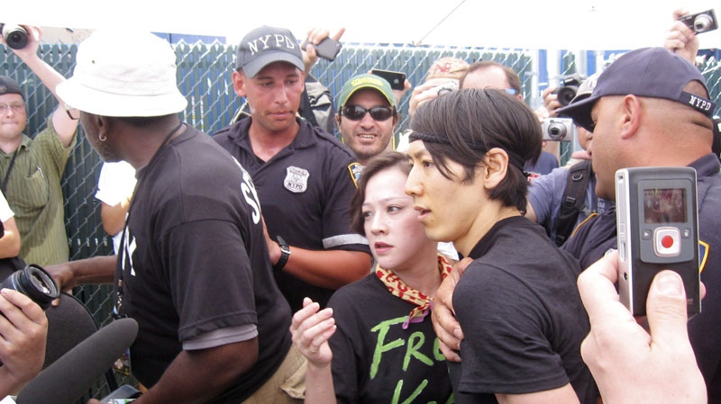 Six-time hot dog eating contest champion Takeru Kobayashi, center, of Japan, is taken into custody by New York police officers after he jumped on stage at the end of the hot dog eating contest in New York's Coney Island on Sunday, July 4, 2010. (AP Photo/Nick Jesdanun)