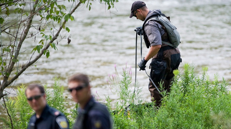 A police search dog unit searches the banks of the Credit River in Hewick Meadows Park in Mississauga, Ont., after police discovered a female severed head on Thursday Aug.16, 2012.  (Aaron Vincent Elkaim /  THE CANADIAN PRESS)