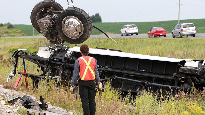 The front wheels of a coach bus that were sheared off in an accident are lifted from the debris at the scene of the crash on Highway 401 in Woodstock, Ontario, Sunday, August 22, 2010. (Dave Chidley / THE CANADIAN PRESS)