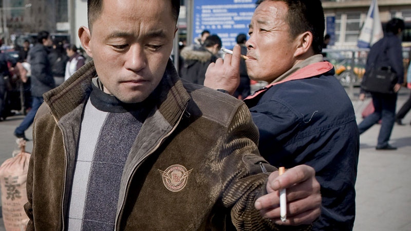 Chinese men smoke cigarettes outside a train station in Beijing, China, Monday, Feb. 16, 2009. (AP / Andy Wong)