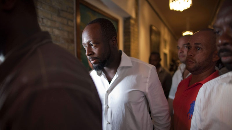 Haitian-born singer and presidential candidate Wyclef Jean, second left, walks surrounded by security after Haiti's Electoral Council rejected his candidacy in Port-au-Prince, Haiti, Friday, Aug. 20, 2010. (AP Photo/Ramon Espinosa)
