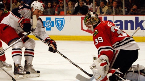 Chicago Blackhawks goalie Cristobal Huet, right, blocks a shot by Columbus Blue Jackets' Raffi Torres during the first period of an NHL hockey game in Chicago,Thursday, Jan. 14, 2010. (AP Photo/Nam Y. Huh)