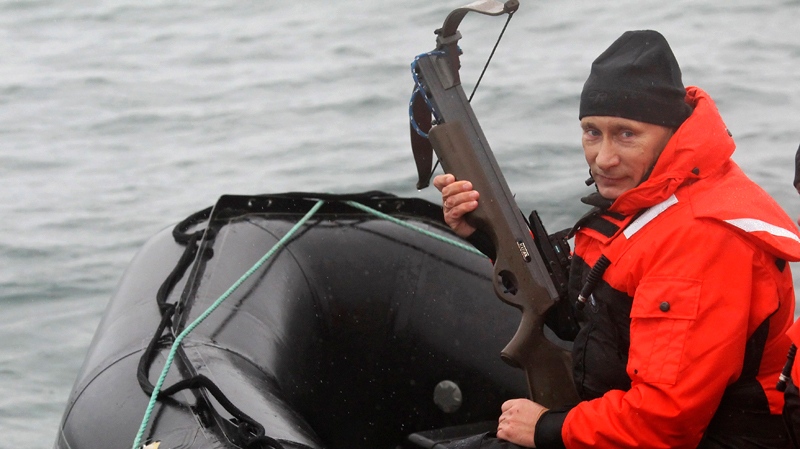 Russian Prime Minister Vladimir Putin holds a crossbow as he sits on a rubber boat at the Olga Harbor of Kamchatka Peninsula during a scientific expedition, to study grey whales on Wednesday, Aug. 25, 2010. (AP Photo/ RIA Novosti, Alexei Druzhinin, pool)