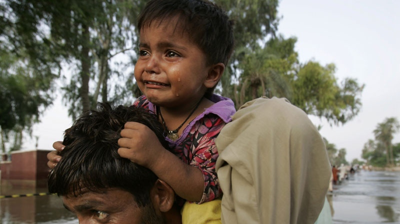 A Pakistani boy cries on top of his fathers shoulder as they cross a flooded road in Baseera, Muzaffargarh district, Punjab Province on Sunday Aug. 29, 2010. (AP Photo/Aaron Favila)
