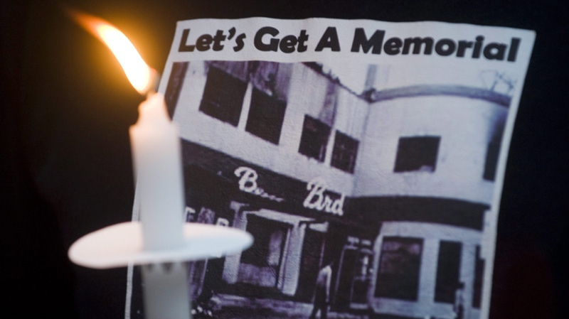 A man holds a candle at the site where the Bluebird Cafe once stood in Montreal on Sept. 1, 2011.