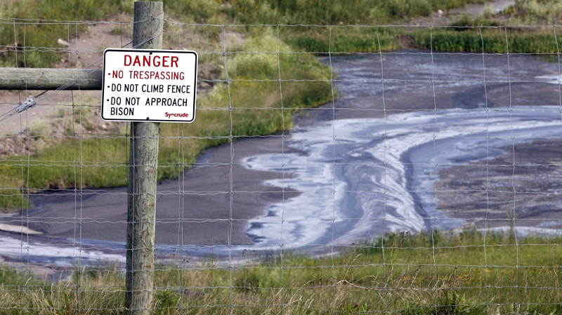 Tailings drain into a pond at the Syncrude oilsands mine facility near Fort McMurray, Alta. on July 9, 2008. (Jeff McIntosh / THE CANADIAN PRESS)  