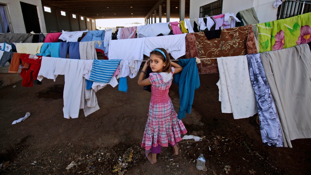 A Syrian girl looks back while checking her laundry