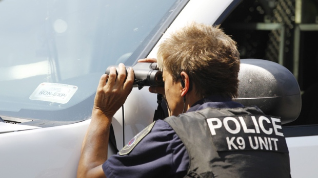 A police officer looks through binoculars on the street in front of the headquarters of the Discovery Channel networks building in Silver Spring, Md., Wednesday Sept. 1, 2010. (AP Photo / Jose Luis Magana)