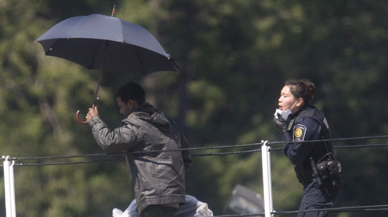 Migrants are escorted from the M V Sun Sea after it was escorted into CFB Esquimalt in Colwood, B.C.,Friday, Aug. 13, 2010. (THE CANADIAN PRESS/Jonathan Hayward)
