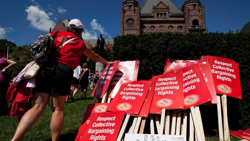 A protester places a sign on a pile in front of Queen's Park following a rally against the "Putting Students First Act" that freezes Ontario Teachers' wages and cuts benefits in Toronto on Tuesday, August 28, 2012. (Michelle Siu / THE CANADIAN PRESS)