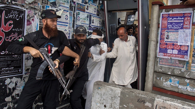 Police escort Khalid Chishti, centre, after his court appearance in Islamabad on Sept. 2, 2012.