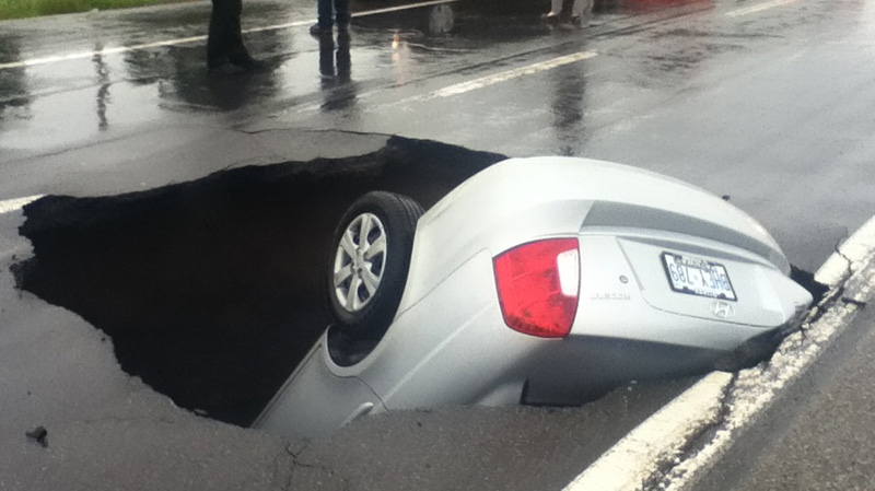 MyNews contributor sends in this image of a car almost completely swallowed by a sinkhole in Ottawa on Tuesday, Sept. 4, 2012. (Jessica Kurchaba/ MyNews.CTV.ca)