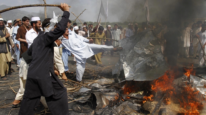 Afghans burn an election signboard while blocking a highway, in reaction to a small American church's plan to burn copies of the Quran, at Jalalabad, east of Kabul, Afghanistan, Friday, Sept. 10, 2010. (AP / Rahmat Gul)