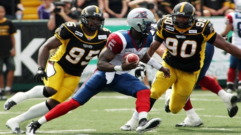 Alouettes quarterback Adrian McPherson tries to escape pressure by Tiger-Cats Justin Hickman (left) and Demonte Bolden during first half CFL action in Hamilton, Ont., Saturday, September 11, 2010. (THE CANADIAN PRESS/Dave Chidley)