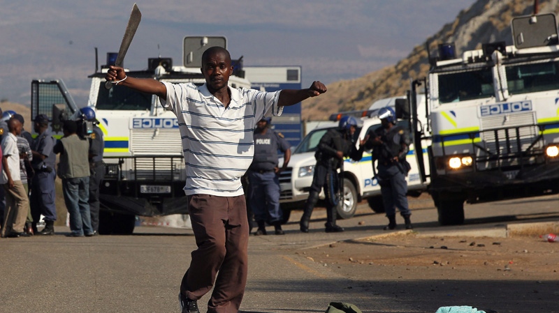 A miner dances in front of police near S. Africa's Lonmin Platinum Mine on Sept. 11, 2012.